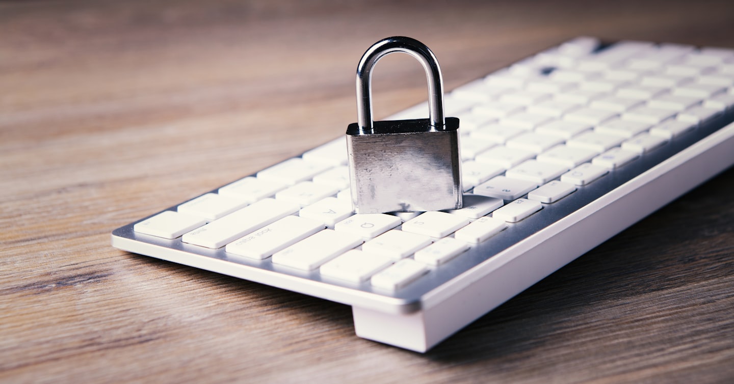 Silver padlock rests on a white computer keyboard.